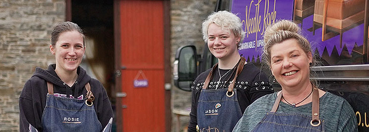 About Us: Meet the Needle Rock team, passionate about restoring antique and vintage furniture, standing outside the workshop.
